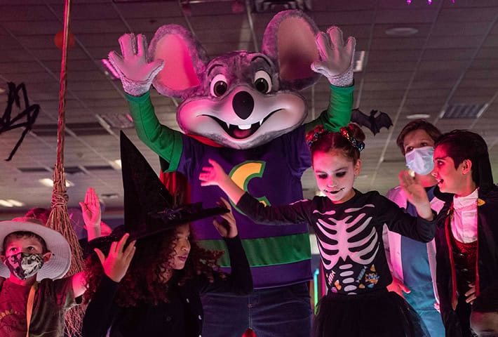 Chuck E. celebrating Halloween with kids on the dance floor.