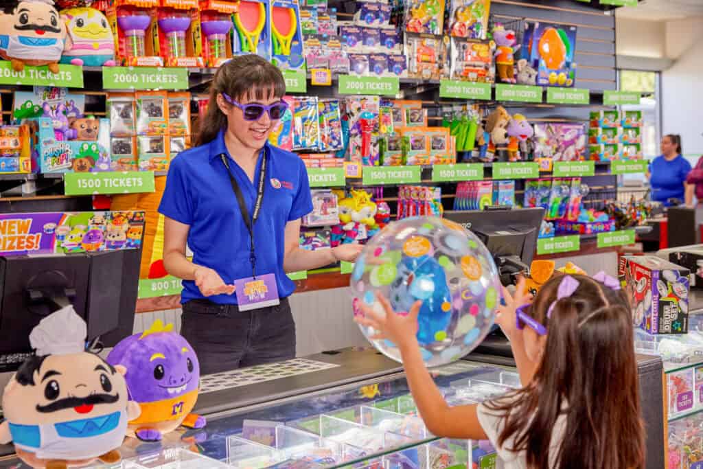 chuck e. cheese cast member handing young girl a prize