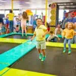 Kids celebrate a birthday party at Chuck E. Cheese, jumping, playing arcade games for kids, enjoying pizza and Fun Pass activities.