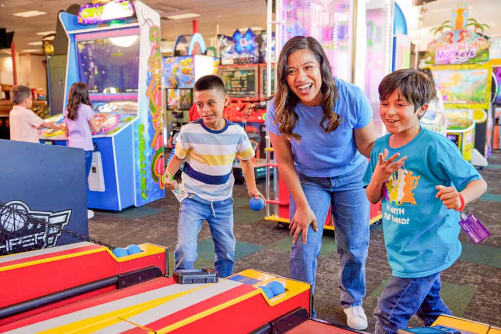 mother playing arcade games with two sons