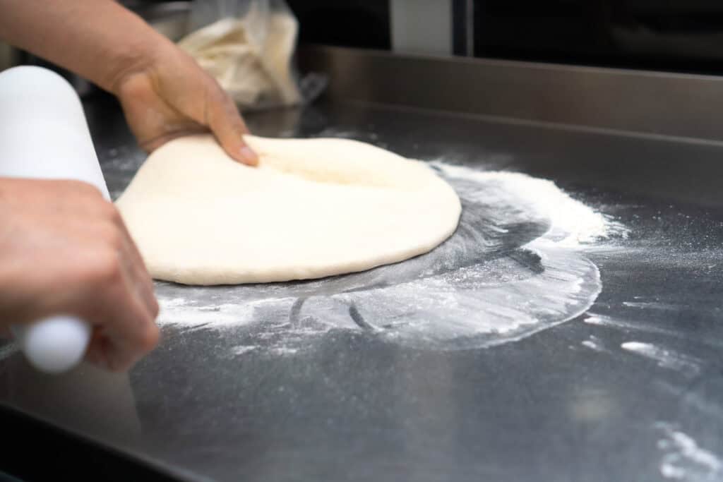Hands shape pizza dough on a floured counter; Fun Pass and arcade games for kids evoke Chuck E. Cheese birthday party setting.