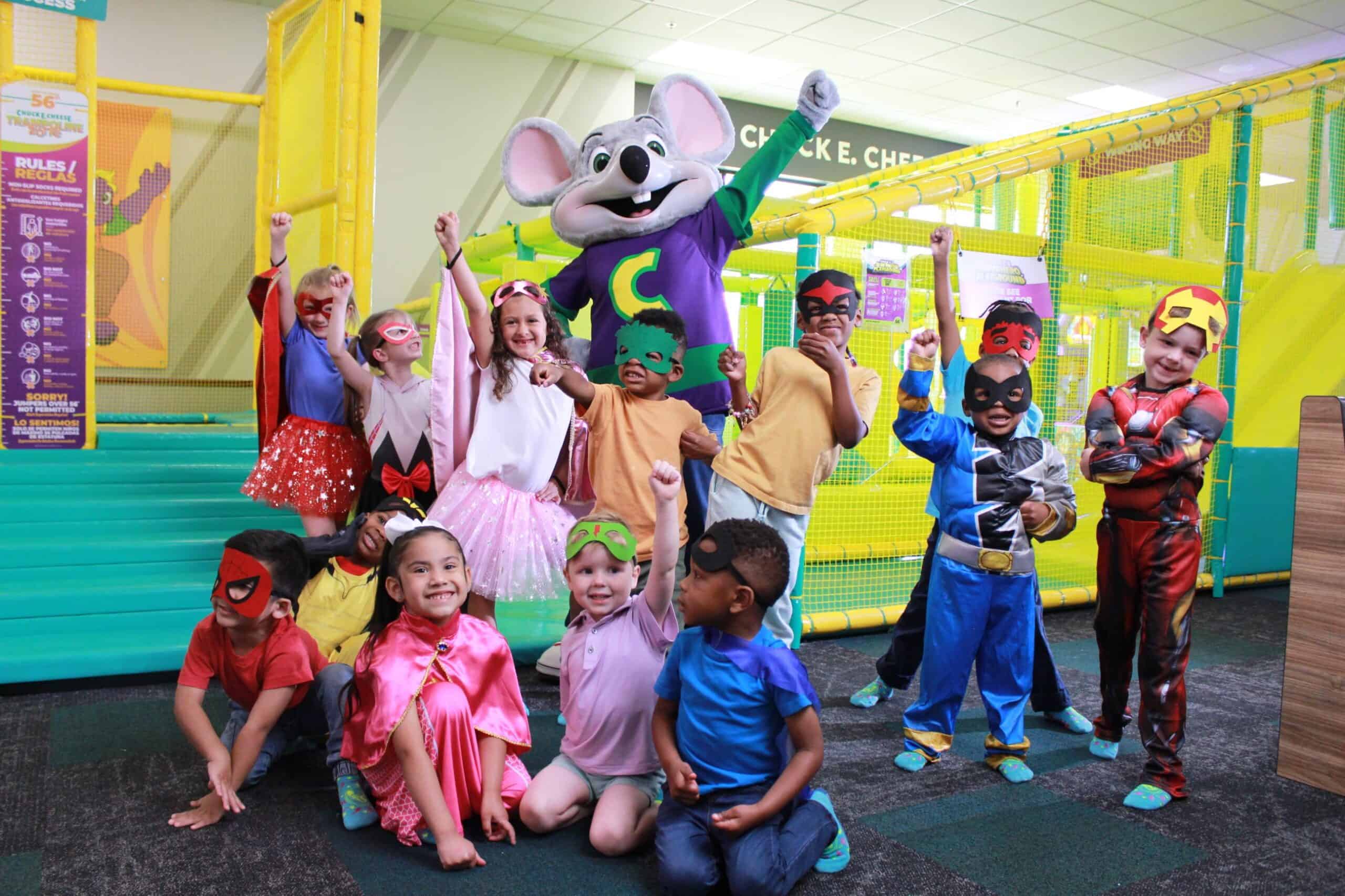 group of kids in costume standing outside the chuck e cheese superhero playground