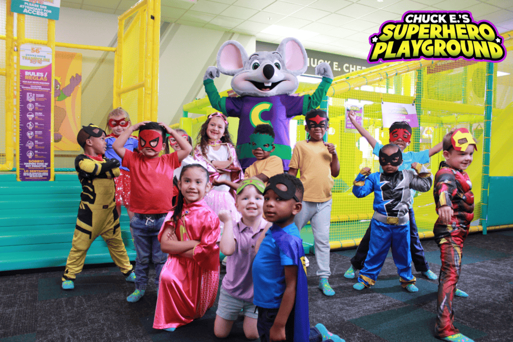Children in superhero costumes with Chuck E. Cheese