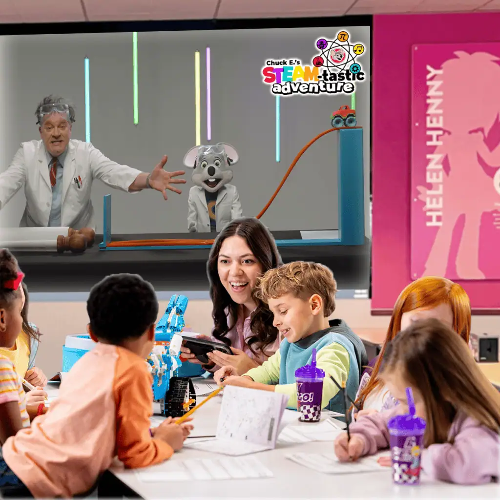 Kids doing STEM activities with a teacher at Chuck E. Cheese near arcade games, pizza, and a Helen Henny poster on the wall.