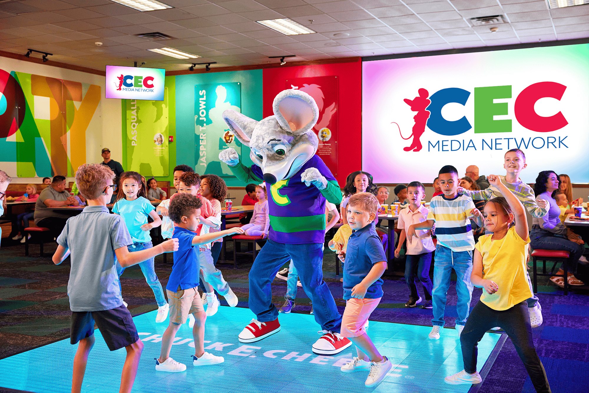 Kids dance on a lit-up floor with Chuck E. Cheese at a birthday party, families watching in the family fun center with arcade games.