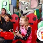 Kids play arcade games at a Chuck E. Cheese birthday party as Chuck E. cheers; Fun Pass and ASDC logo appear in the scene.