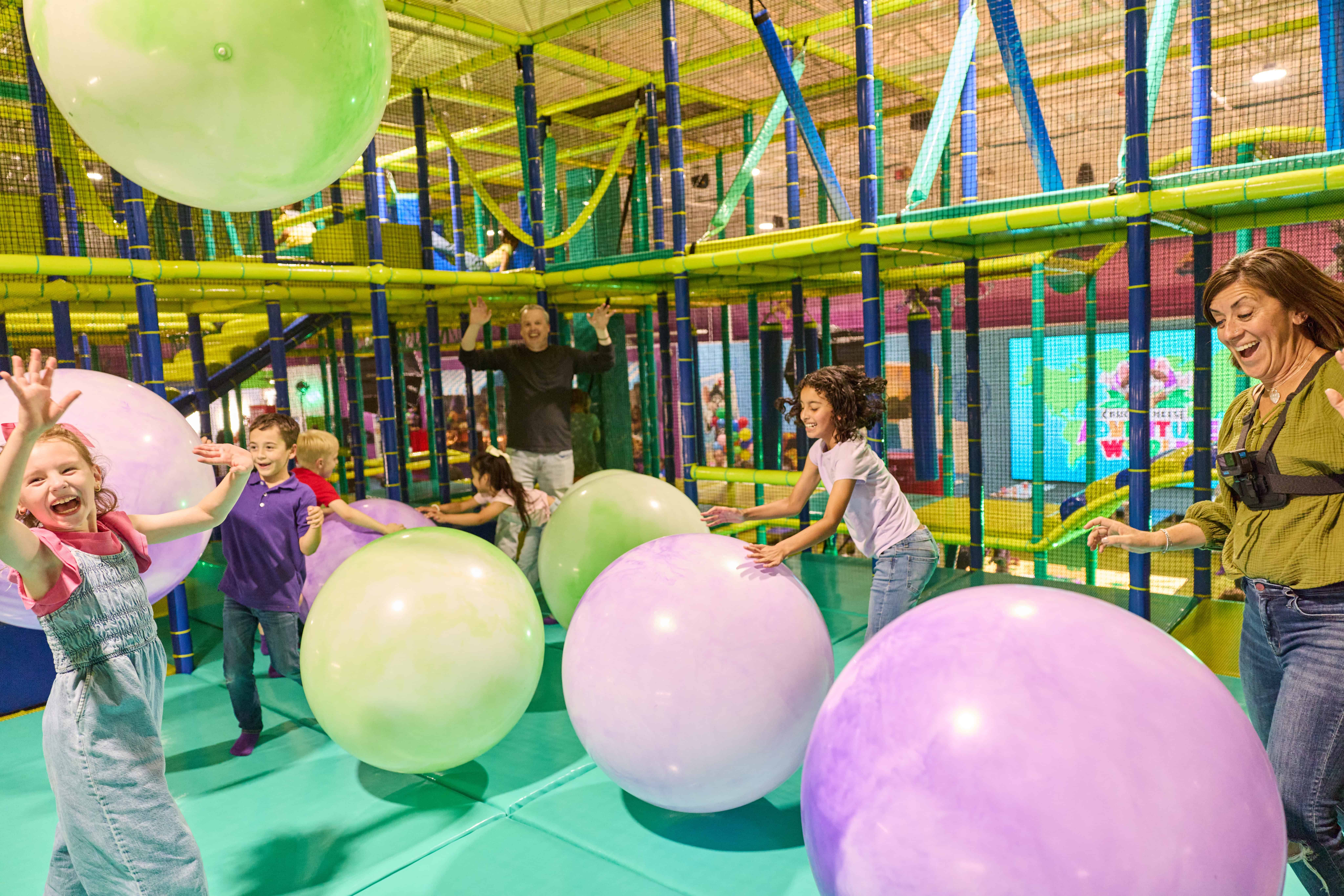 Kids play with pastel balls and climb in Chuck E. Cheese's indoor playground