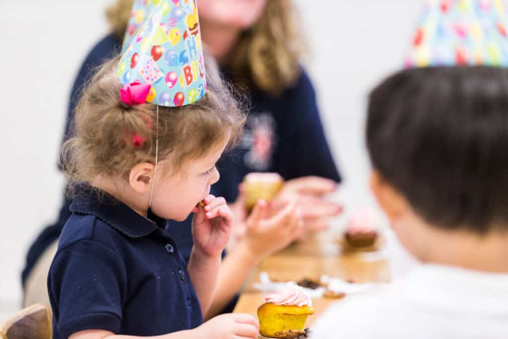Birthday party in Chuck E. Cheese party room; kids ages 4–6 enjoying cupcakes, joyful.