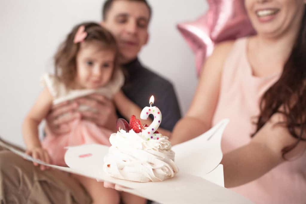 Family with adults and kids at a Chuck&nbsp;E.&nbsp;Cheese birthday party in the party room, host attentive in the background