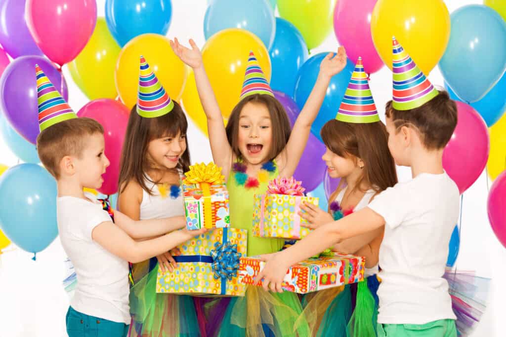 Birthday party in Chuck&nbsp;E.&nbsp;Cheese party room: kids ages 6–8 in hats with balloons and cake