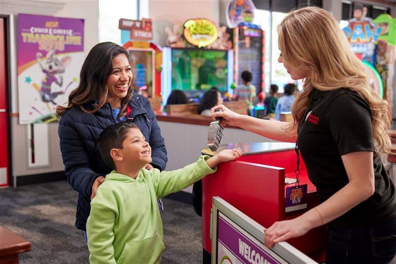 Chuck E. Cheese team member stamping a child's arm at the Kid Check station