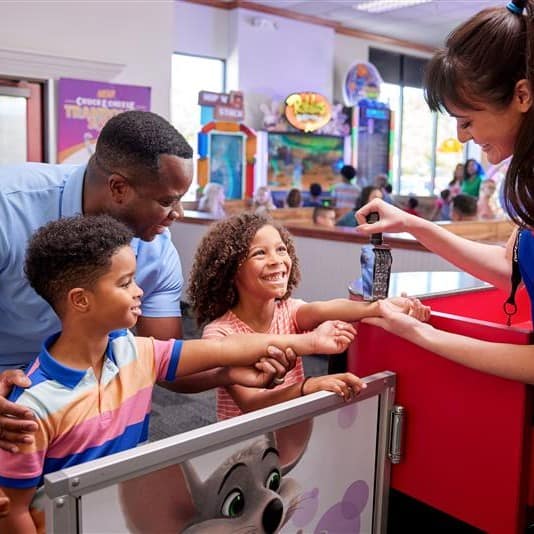 Family receiving Kid Check UV stamps at a Chuck E. Cheese entrance