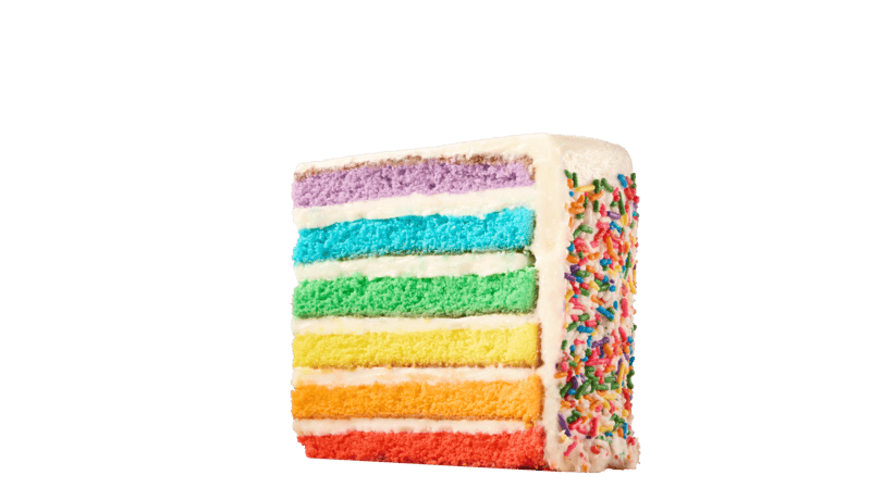 Rainbow layer cake slice with white frosting and sprinkles, birthday party treat at Chuck E. Cheese family fun center.