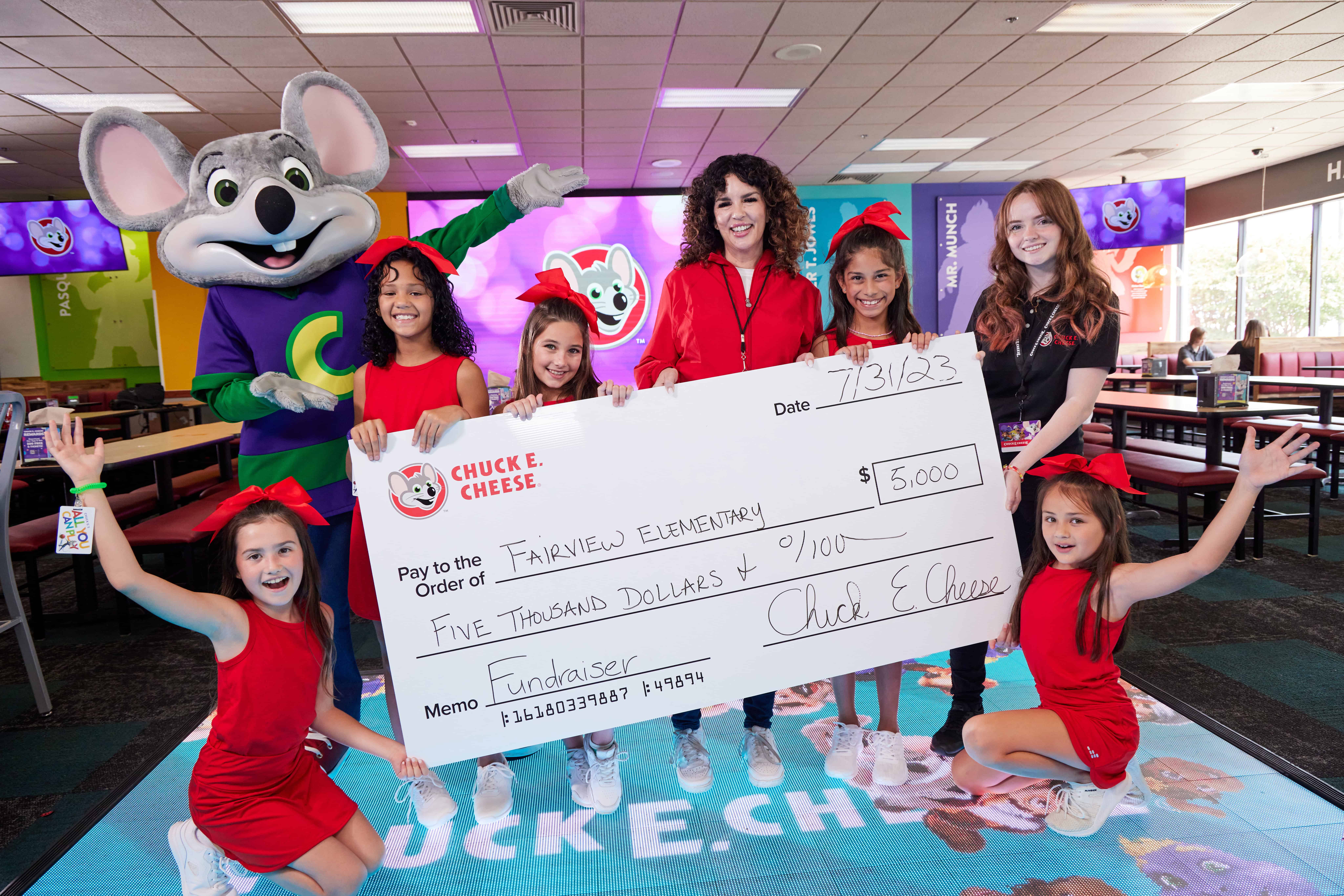 Young girls holding a donation check at a Chuck E. Cheese fundraiser event