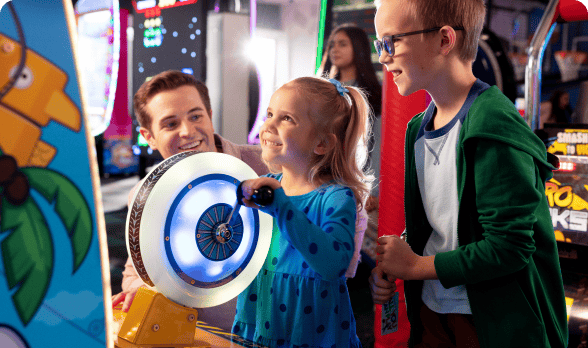 Smiling young girl playing arcade games at Chuck E. Cheese, age 4-5, pure joy