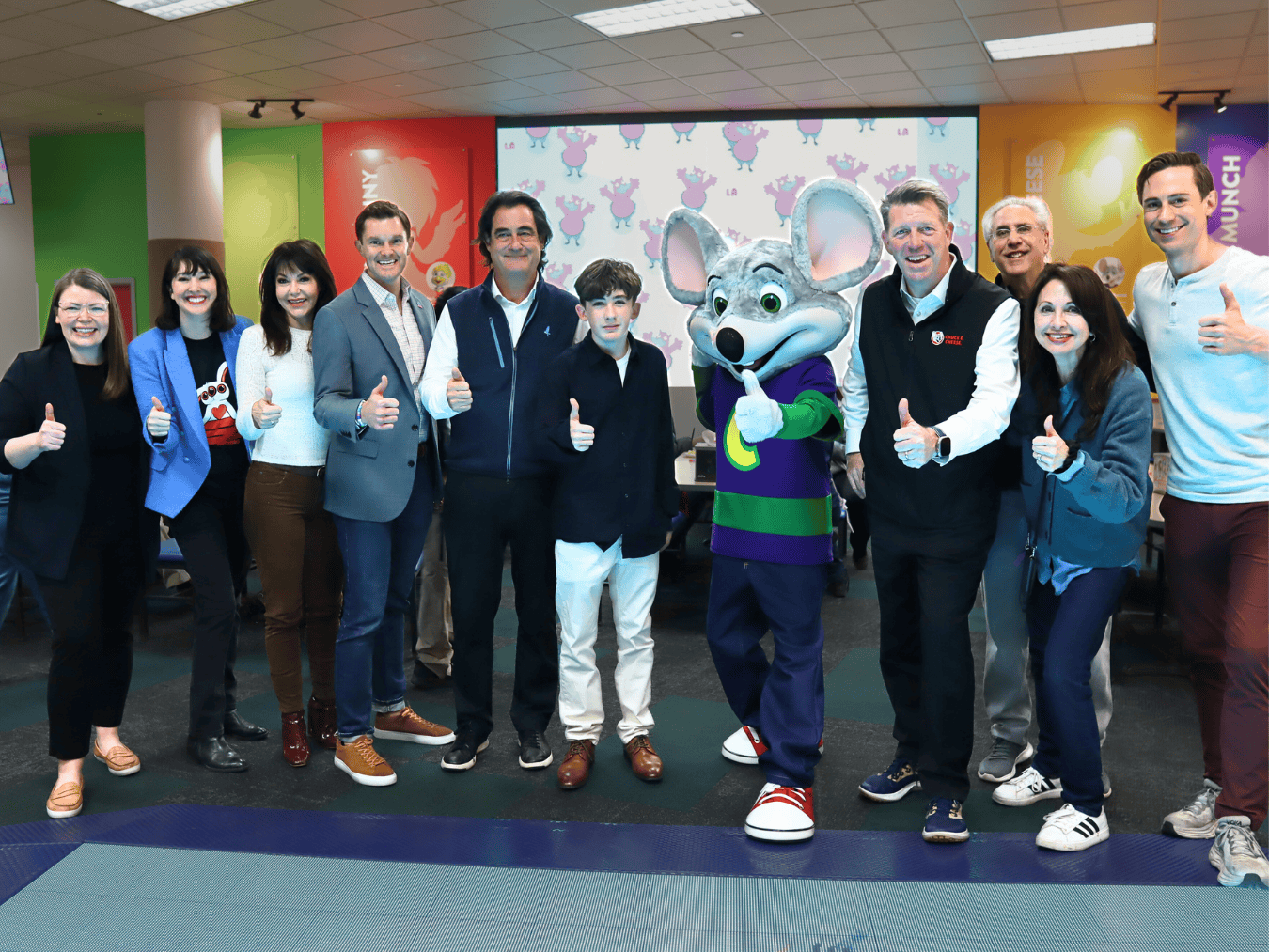 Kids and adults with Chuck E. Cheese mascot at a birthday party