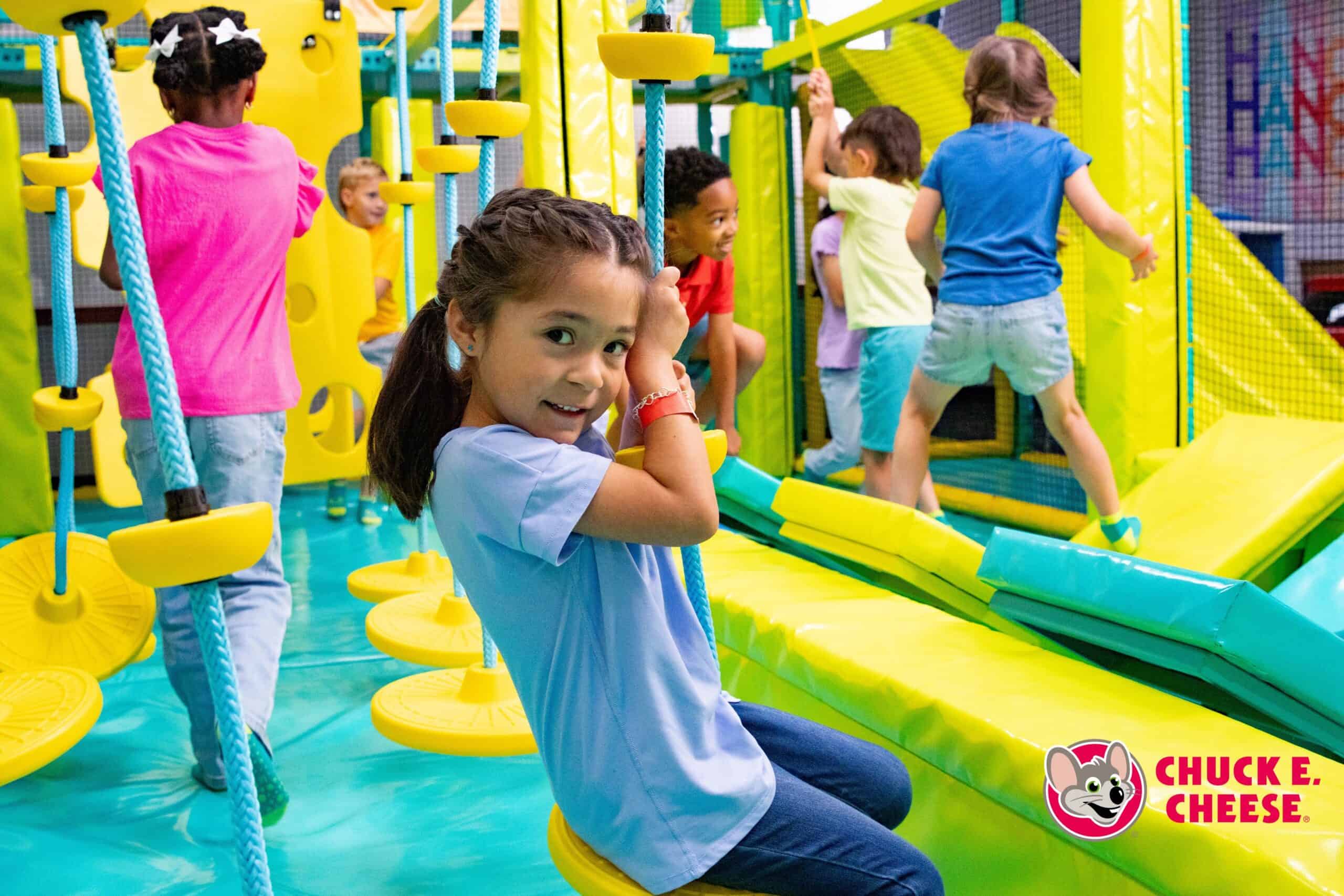 Kids playing in the Adventure Zone active play area at Chuck E. Cheese, including trampolines and climbing structures