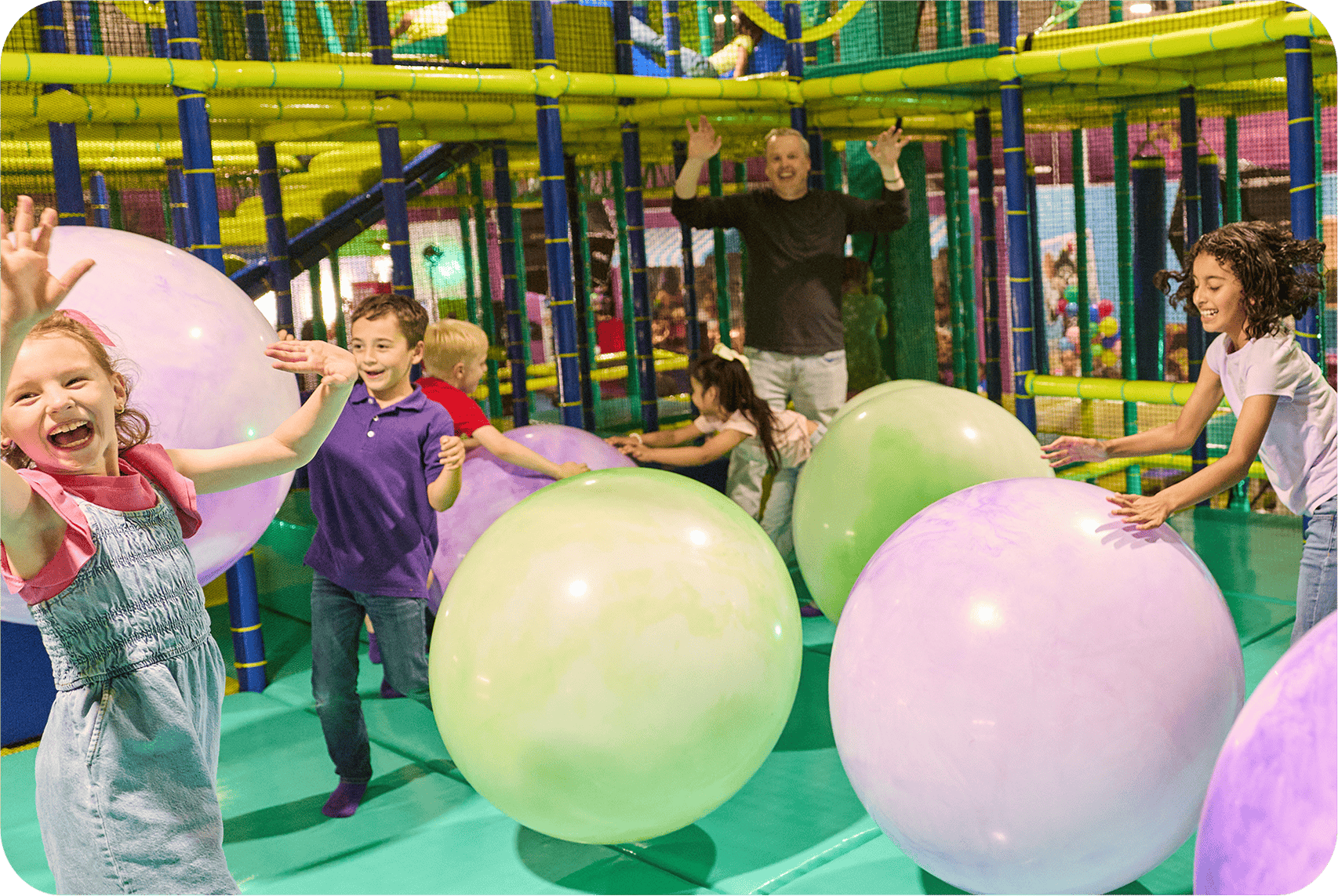 Kids play with pastel inflatable balls among colorful climbing nets at Chuck E. Cheese, a family fun center for kids' birthday parties.