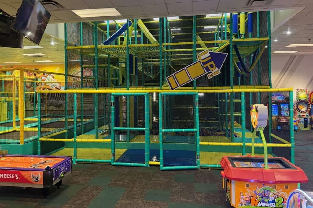 Chuck E. Cheese family fun center with yellow-green climbing tubes, arcade games, air hockey, and birthday party area.