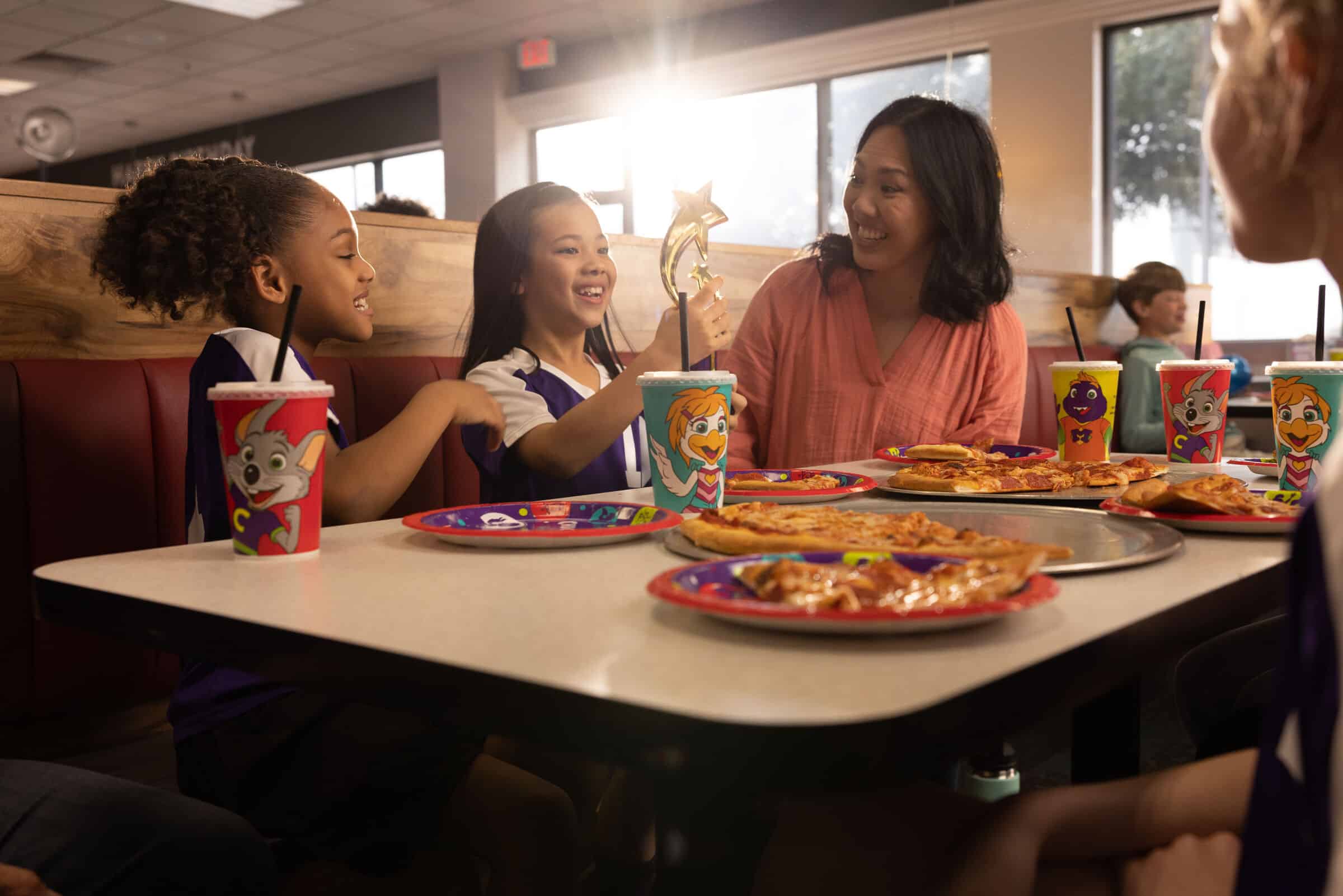 Kids at Chuck E. Cheese group party enjoying pizza and games — what awaits after a quick online booking