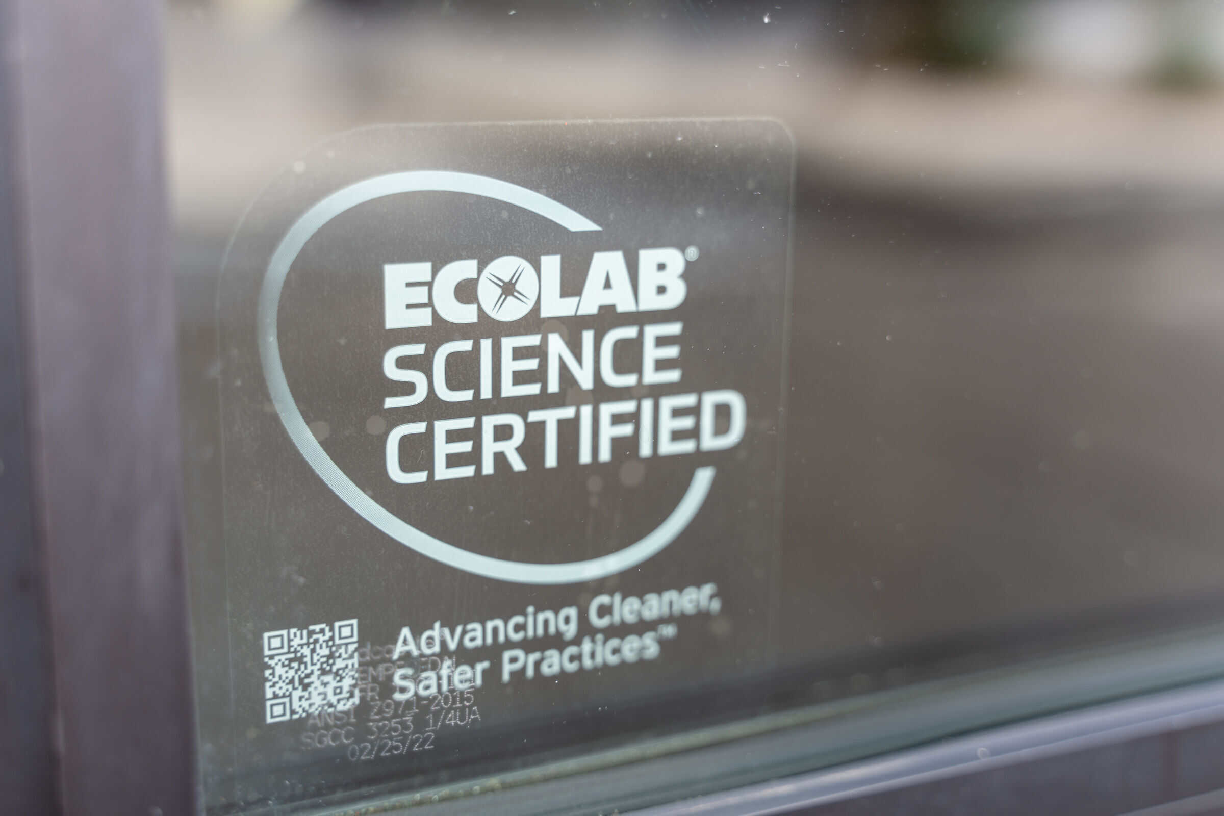 ECOLAB SCIENCE CERTIFIED sticker with safety tagline and QR code on Chuck E. Cheese glass, seen from outside the family fun center.