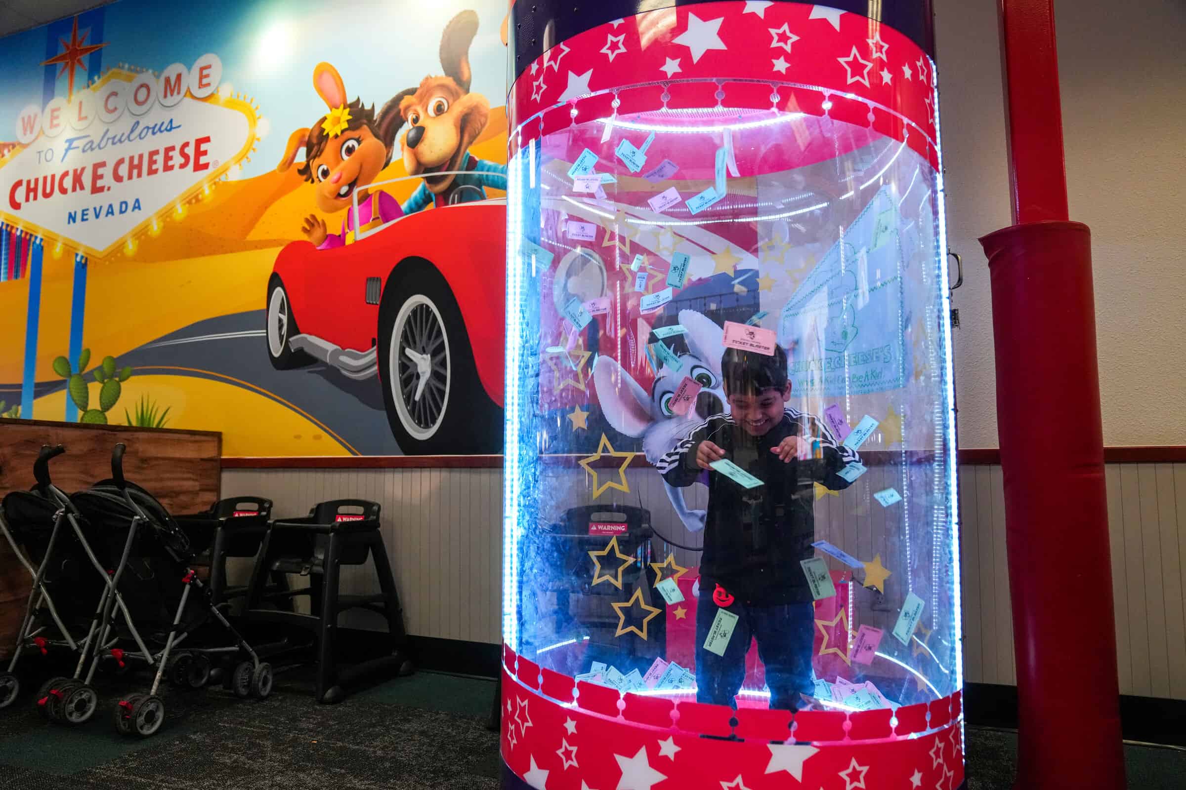 Smiling boy catching prize tickets in the Ticket Blaster at Chuck&nbsp;E.&nbsp;Cheese.