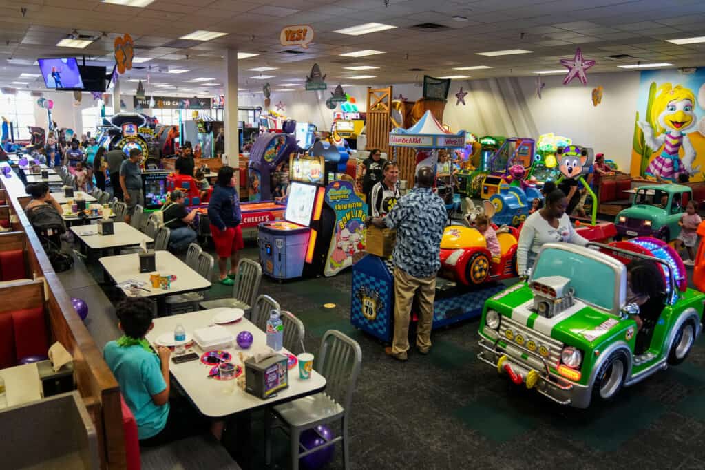 Kids and families enjoying arcade games and dining at a Chuck E. Cheese location.