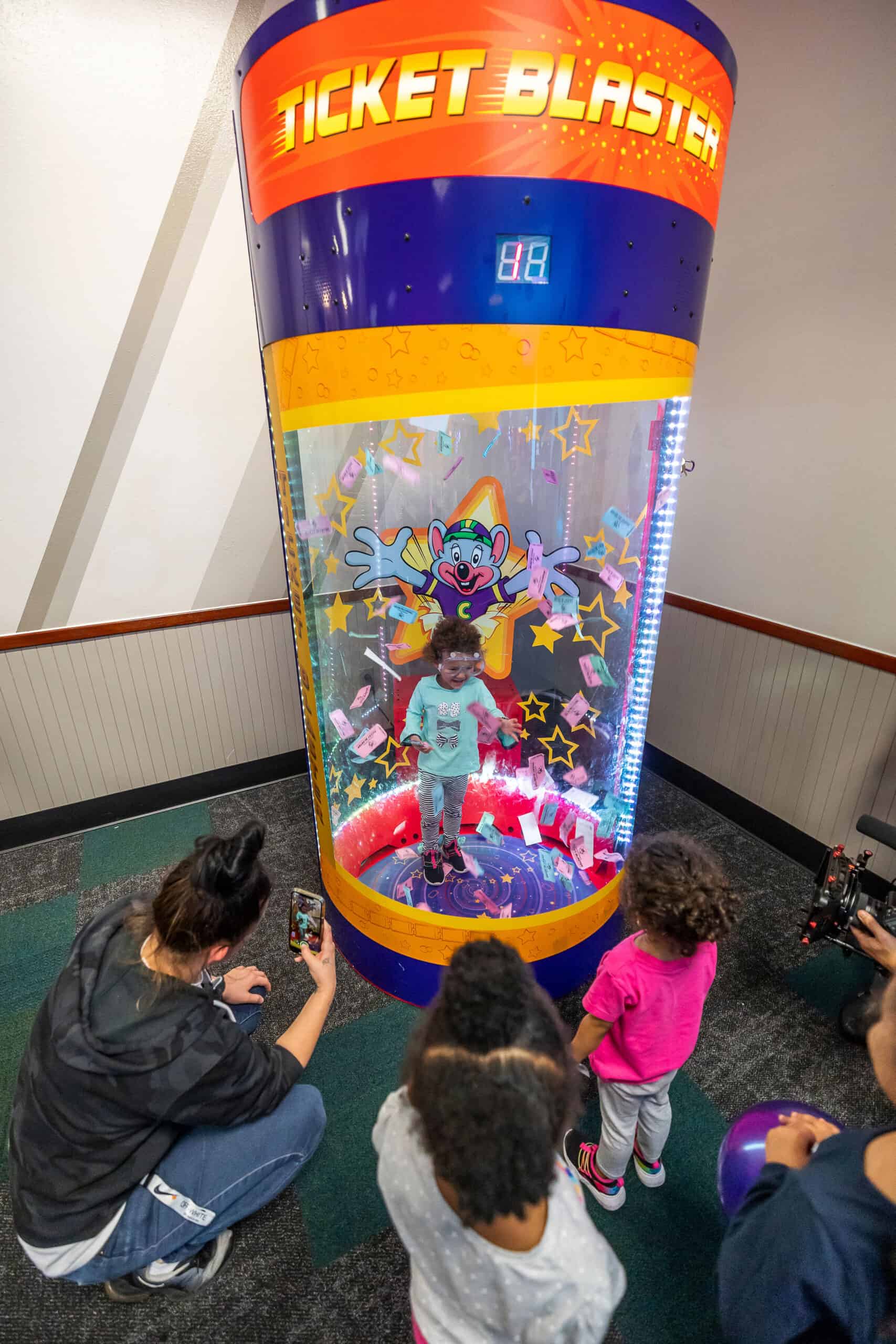 Young girl excitedly catching prize tickets inside the Ticket&nbsp;Blaster at Chuck&nbsp;E.&nbsp;Cheese.