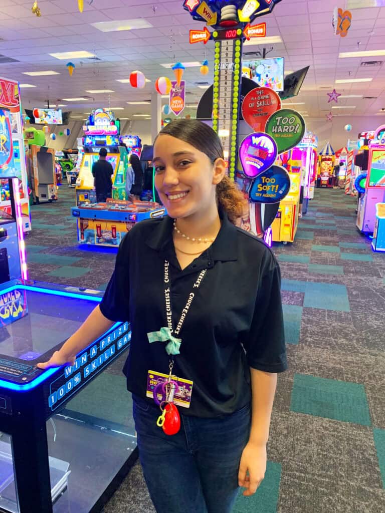 Chuck E. Cheese team member smiling in the arcade, ready to assist guests.