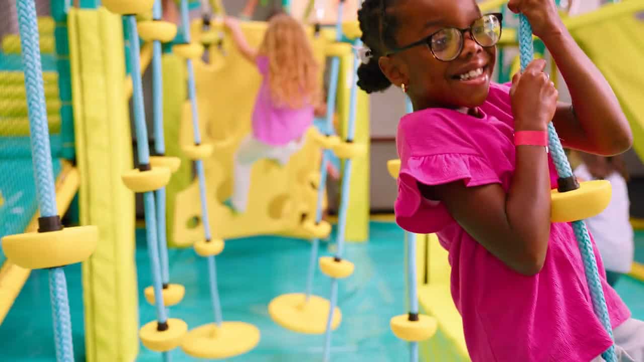 Girl climbing a rope ladder in the Chuck E. Cheese Adventure Zone