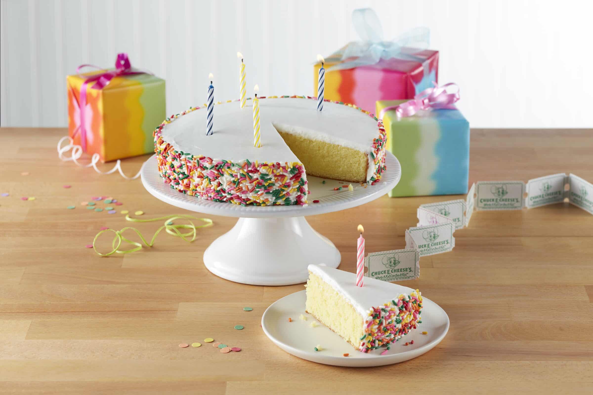 Birthday cake with lit candles in the Chuck E. Cheese party room.
