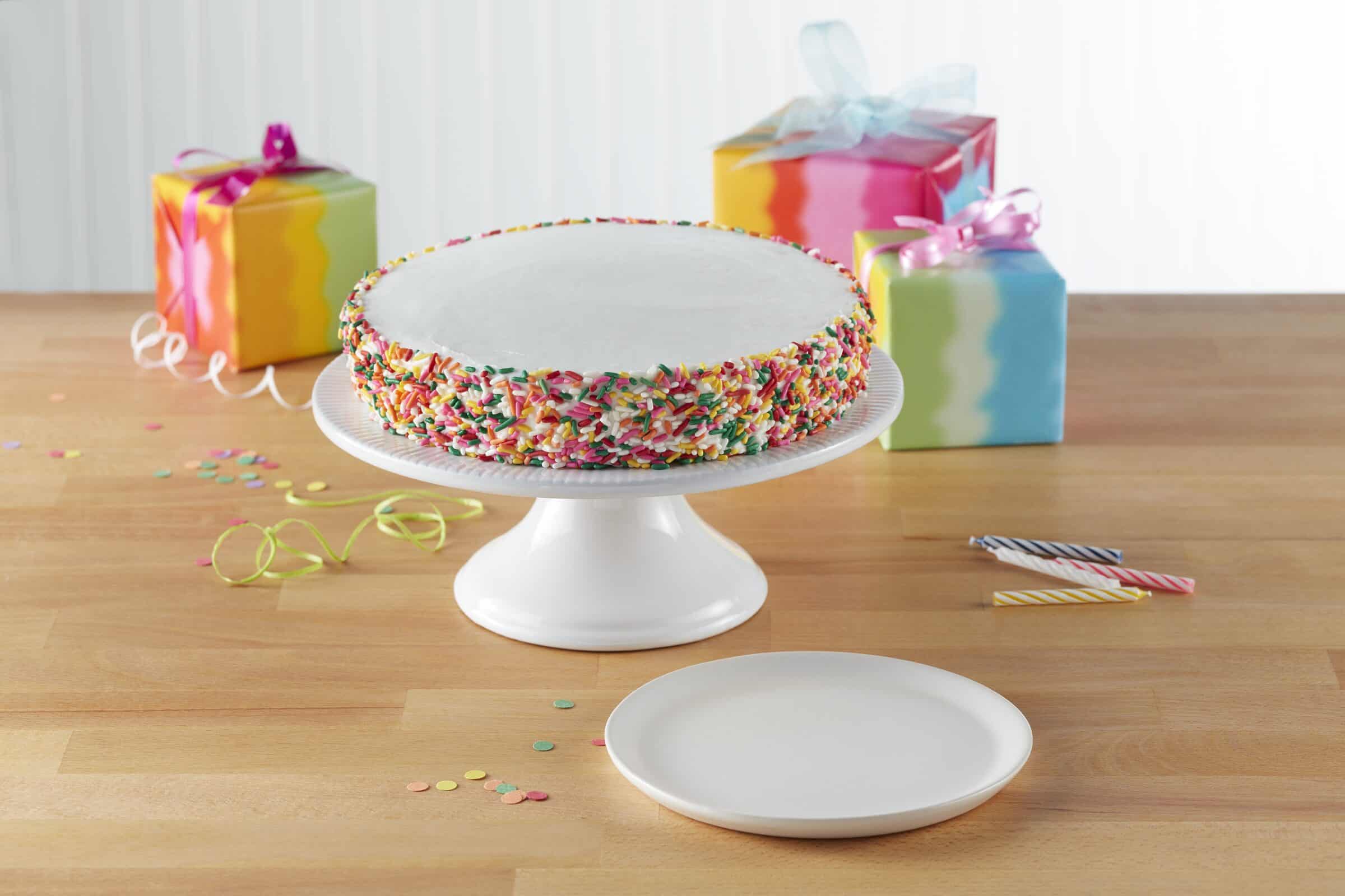 Birthday cake with sprinkles, rainbow gifts, and confetti in Chuck E. Cheese party room.